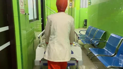 Nurses wearing orange uniforms pushing a hospital bed 库存影片 333836312