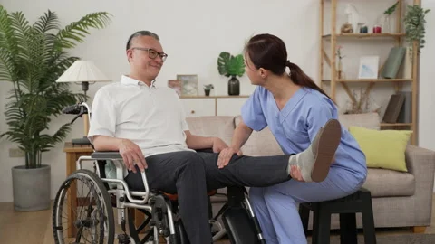 Nursing aide helping elderly male exercise leg Stock Footage 204789605