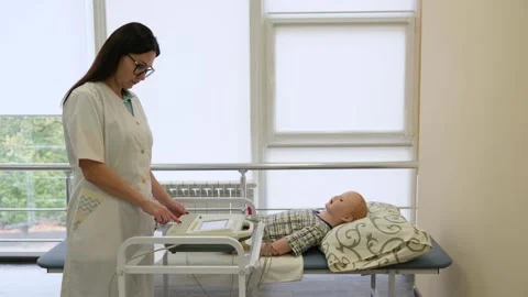 Nursing student learning to operate an electrocardiogram machine, performing a Stock Footage 319631743