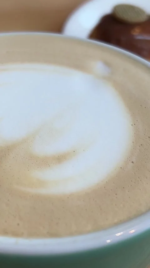 Nut and chocolate eclair and glass of flat white coffee on black plate Stock Footage 265352976