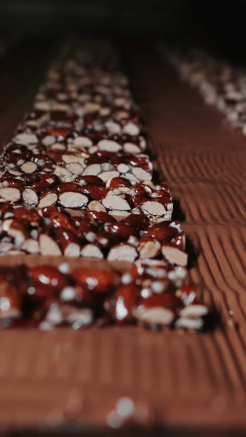 A nut bar moves along a conveyor belt at a confectionery factory. Stock Footage 293659002