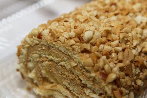 Nut-covered layered cake roll with creamy filling on plate. Stock Photos