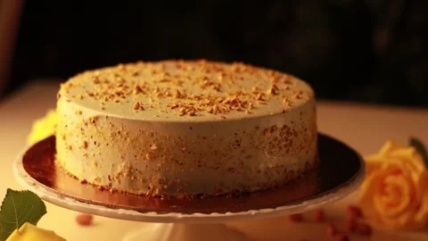 Nut Cream Cake on a Cake Turntable in a Cozy Atmosphere with Yellow Roses Stock Footage 241324214