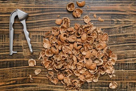 Nut shells and a nutcracker scattered on a wooden surface after a snack time Foto stock