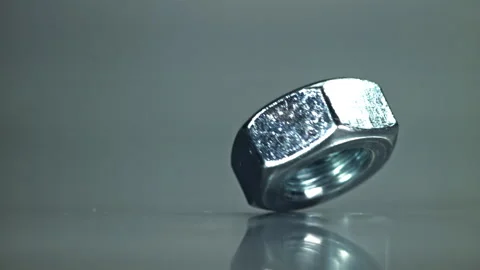 The nut is spinning on a metal table. Filmed on a high-speed camera at 1000 fps. Stock Footage 307930549