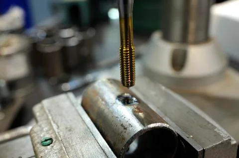Nut tap making thread on the tube section, tapping machine Stock Photos