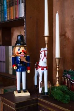 Nutcracker doll and horse on the table with candles in the library. Book is the Stock Photos
