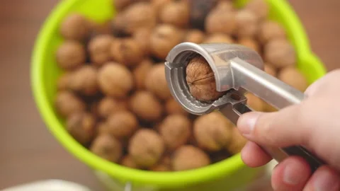 Nutcracker in hand and walnut close-up against the background of a bucket with Stock Footage 156627450