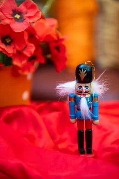 Nutcracker soldier with white beard, red fabric, and vibrant flowers backgrou Stock Photos