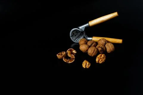 Nutcracker with some walnut at black background Stock Photos