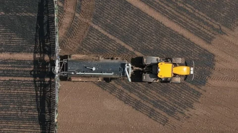 Nutrient injection tractor applying liquid manure across cultivated farmland Stock Footage 335815834