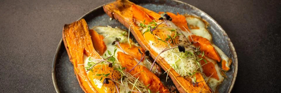 Nutrient-rich eggs baked inside sweet potatoes sit on a rustic plate. Fresh.. Stock Photos