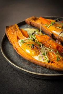 Nutrient-rich eggs baked inside sweet potatoes sit on a rustic plate. Fresh m Stock Photos