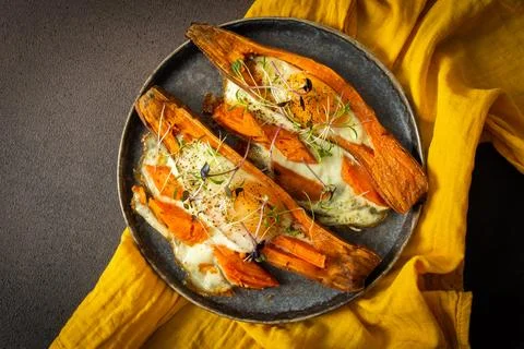Nutrient-rich eggs baked inside sweet potatoes sit on a rustic plate. Fresh m Stock Photos