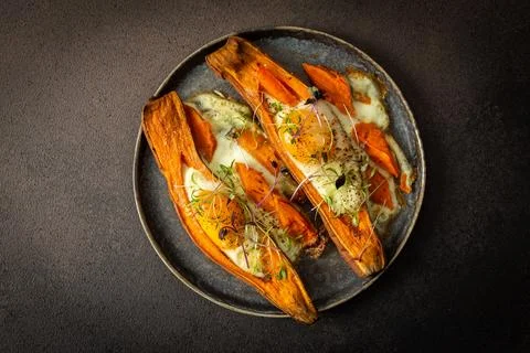 Nutrient-rich eggs baked inside sweet potatoes sit on a rustic plate. Fresh m Stock Photos