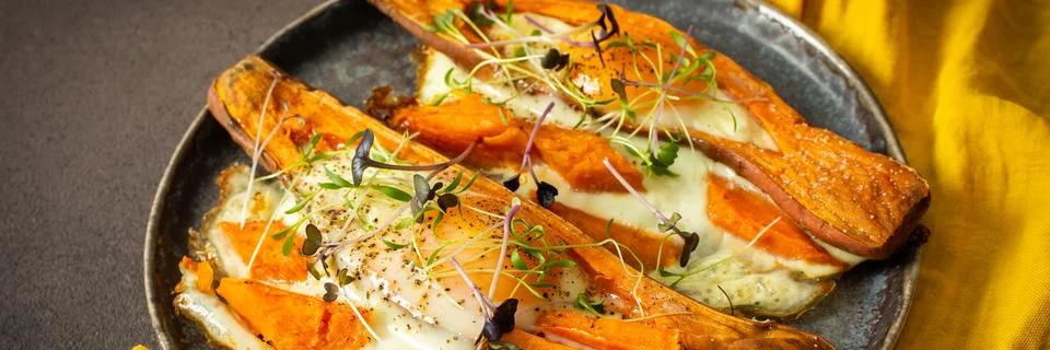 Nutrient-rich eggs baked inside sweet potatoes sit on a rustic plate. Fresh.. Stock Photos