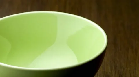 Nutrient rich plain rolled oats pouring into green ceramic bowl with wooden b Stock Footage 63360962