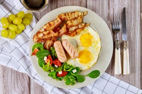 Nutrition breakfast with eggs, hot dogs, bacon and salad. Stock Photos