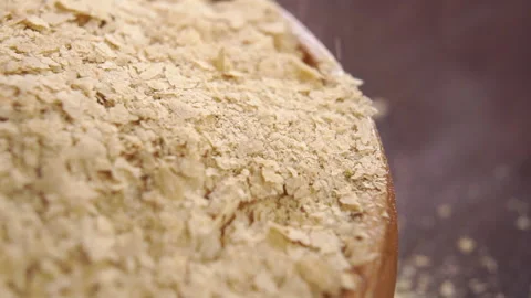 Nutritional brewers yeast flakes falling on a full rustic wooden bowl Stock Footage 167818196