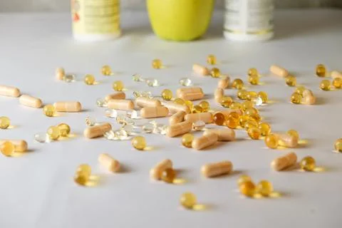 Nutritional supplements spread across a table with fresh produce nearby Stock Photos
