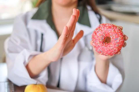 Nutritionist shows a sugary donut as an example of an unhealthy choice and its Stock Photos