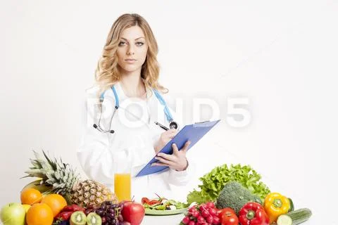 Nutritionist writing medical records and prescriptions with fresh oranges and Stock Photos