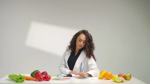 Nutritionist Writing Notes During Healthy Diet Planning Session at Desk Stock Footage 337710080