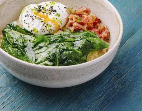 Nutritious breakfast bowl featuring a poached egg, wilted greens, and crispy Stock Photos