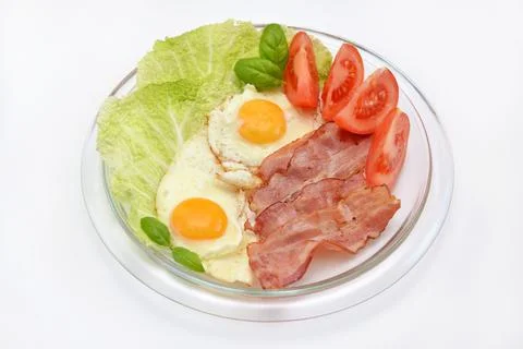 Nutritious breakfast scrambled eggs with bacon and vegetables on a plate Stock Photos