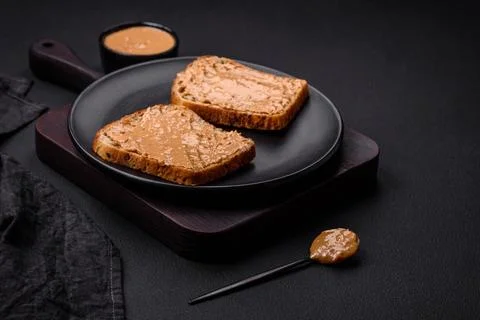 Nutritious sandwich consisting of bread and peanut butter on a black cerami.. Stock Photos