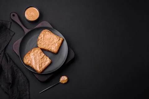 Nutritious sandwich consisting of bread and peanut butter on a black cerami.. Foto stock