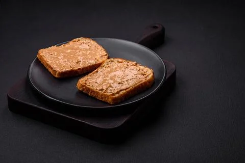 Nutritious sandwich consisting of bread and peanut butter on a black cerami.. Stock Photos