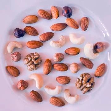Nuts, Almonds, Hazelnuts, Walnuts, Cashew Nuts on a White Plate. Healthy Orga Foto stock