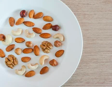 Nuts, Almonds, Hazelnuts, Walnuts, Cashew Nuts On White Plate On A Wooden Tab Stock Photos