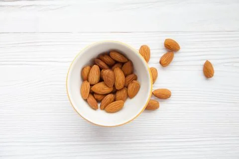 Nuts almonds in a small plate on a background of white wood Stock Photos