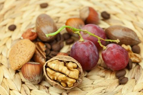Nuts and grapes on a wicker mat Stock-Fotos