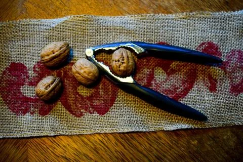 Nuts and a nutcracker are on a linen napkin. Stock Photos