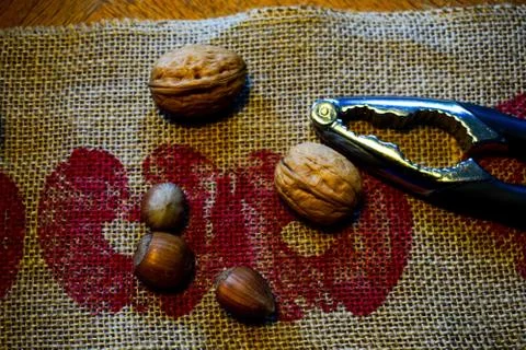 Nuts and a nutcracker are on a linen napkin. Stock Photos
