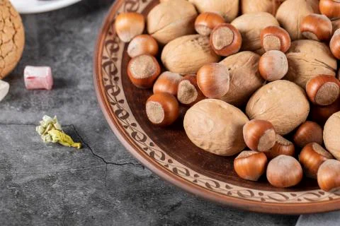 Nuts and walnuts in a decorative platter on a piece of marble Stock Photos