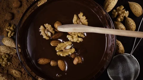 Nuts are mixed in chocolate with a spoon. Slow mo Stock Footage 74732788