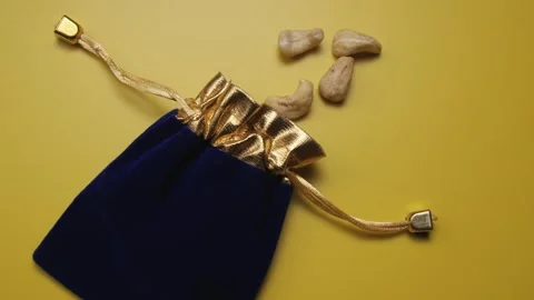 Nuts are poured out of a suede dark blue pouch moving on a yellow background 스톡 동영상 277541109