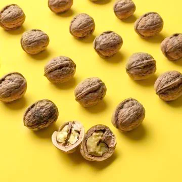Nuts arranged in rows with a yellow background. Stock Photos