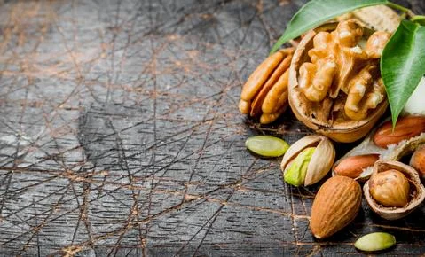 Nuts background. Assortment of different nuts with green leaves . Stock Photos