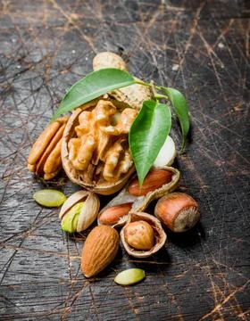 Nuts background. Assortment of different nuts with green leaves . Stock Photos