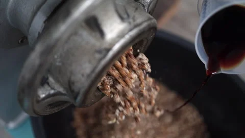 Nuts, dates extrude into mixing bowl, syrup is added from measuring cup Stock Footage 305134583