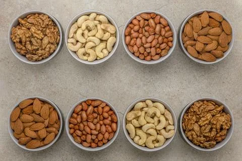Nuts of different varieties, top view. The mixed nuts lie in bowls on a stone Stock Photos