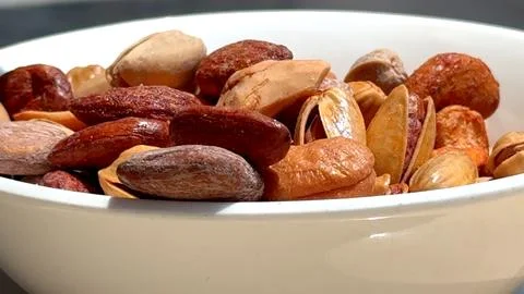 Nuts fall into white bowl, offering natural source of energy, health benefits Stock Photos