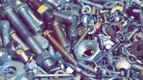 Nuts falling on pile of bolts lying on workshop table Stock Footage 115543780