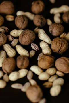 Nuts. Organic different nuts: walnut, peanut and pistachio on black backgroun Stock Photos