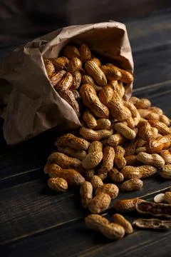 Nuts peanuts in a shell on a wooden background in a craft bag Stock Photos